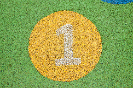 Number one in a multicolored rubber outdoors children's playground.