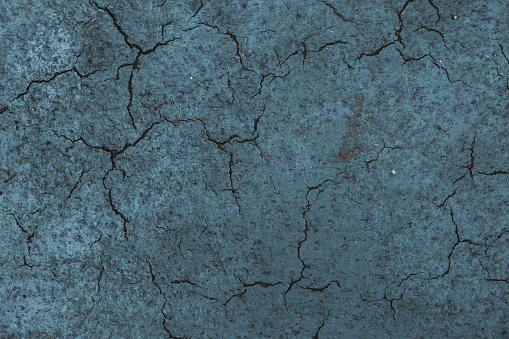 cracked asphalt texture in dark navy blue. background of cracks on asphalt