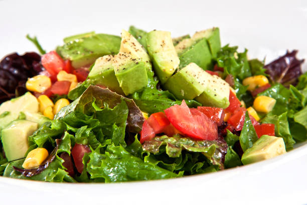 Avocado salad with corn, tomato and fresh lettuce, close up view
