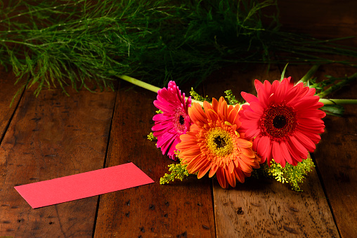 Gerbera flowers with red color label over a rustic wooden table