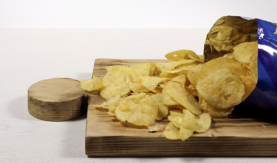 Opened package of chips on a wooden stand.