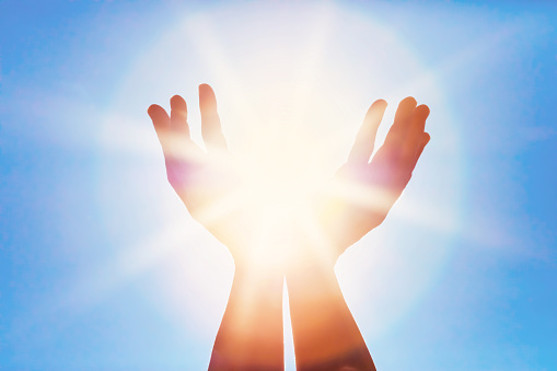 A DSLR photo of hands as if holding the sun with beautiful sunbeams.