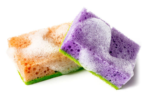 Close-up of a pair of wet sponges for washing dishes with soap sud. Isolated on a white background.