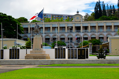 Nouméa, South Province, New Caledonia: Gally Passebosc Barracks, 19th century French military building - main façade with French tricolor and the World War I memorial (Monument aux Morts, 1924, unknown author) with its wall of names, dedicated 'To the Caledonians and Hebrideans who died for France' - Olry Street / Bir-Hakeim Square, Quartier Latin.