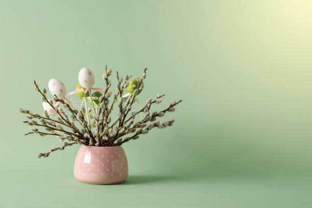 Easter eggs and pussy willow twigs with catkins in a vase. Space for copy.