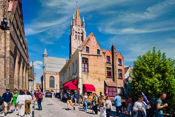 Bruges,Belgium-June 3, 2023 - A tour guide with furled umbrella leads a group of visitors through the ancient streets and alleyways of Bruges, Belgium on a early June afternoon.