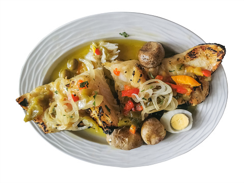 View of a typical Portuguese dish, named Bacalhau à Lagareiro, grilled cod fish, potato, egg, onions, green and red peppers and garlic, with olive oil, white background...