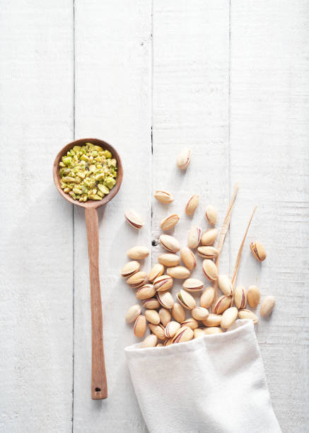 Pistachios in a spoon on a white wooden background