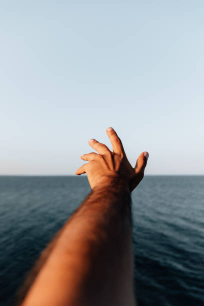 istock outstretched hand is over the Aegean Sea at sunset 1970992097