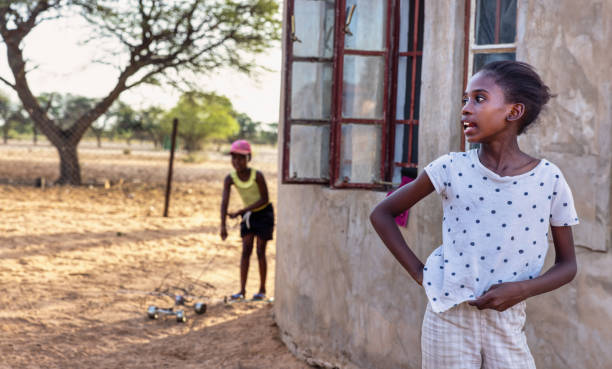 village african kids , two sisters talking and playing in the yard with a galimoto wire toy car