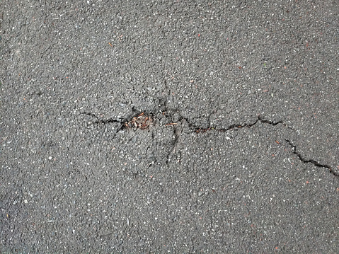 A crack on the asphalt surface of the road on the whole background. View from above