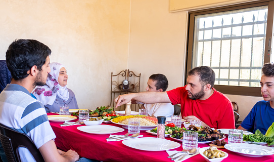 Happy arabic muslim family eating together in a family meeting for iftar in ramadan