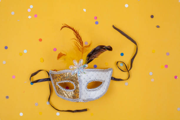 istock Venetian white and gold mask isolated on a yellow background 1971054376