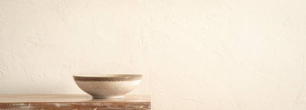 istock Minimalist Ceramic Bowl on Wooden Table Against a Neutral Textured Wall 1971071993