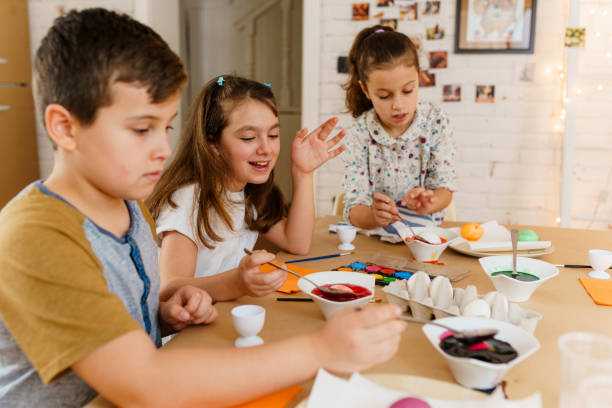 istock Cute little kids having fun with coloring Easter eggs with various colors 1971073035