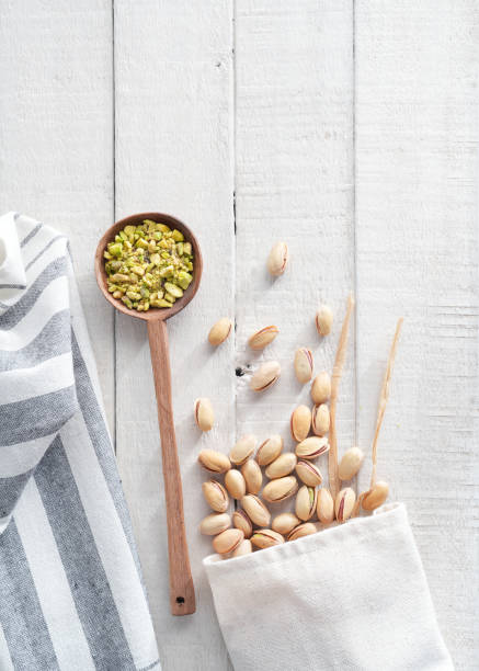 Pistachios in a spoon on a white wooden background