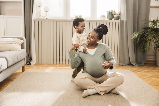 Expecting mother and baby son exercising Yoga at home.