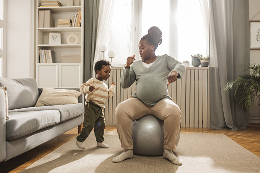 Expecting mother and baby son exercising Yoga at home.