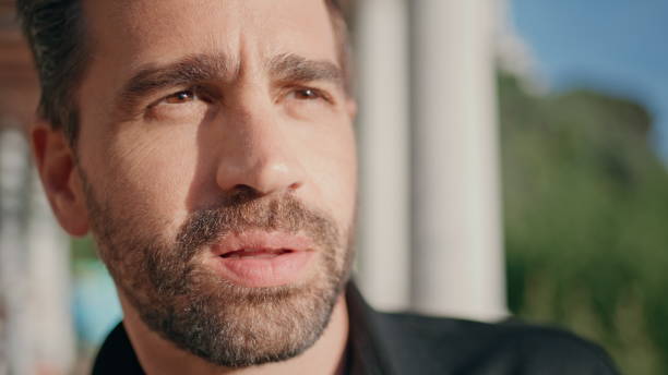 Thoughtful man face looking distance at sunshine square closeup. Latin adult artist waiting inspiration thinking at summer park. Handsome unshaven guy standing outside at sun beams. People lifestyle