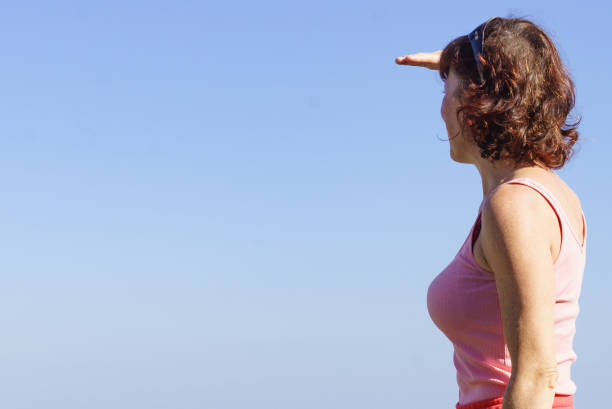 Female person against blue sky looking at horizon enjoying fresh air
