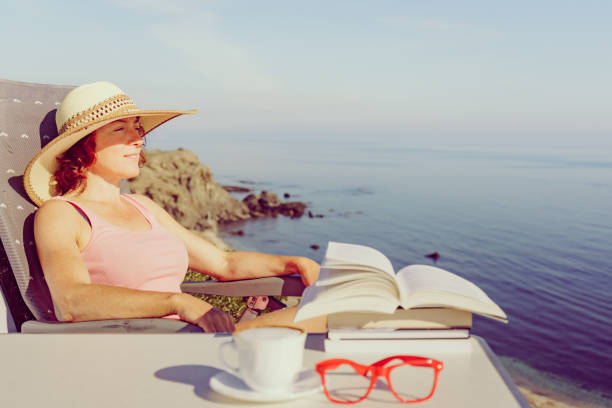 Young Woman Reading a Book in Her Chair by the Sea