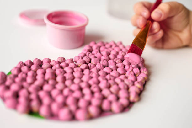 Close-up of assorted colorful beads organized in a plastic storage box with pink tweezers, used for jewelry making and crafts.