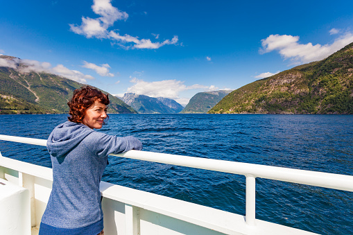 Tourism vacation and travel. Tourist woman on cruise ship enjoying fjord Sognefjord view in Norway, Scandinavia Europe.