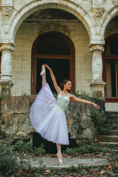 istock Graceful ballerina dancing in front of rustic classicist building. 1971347140