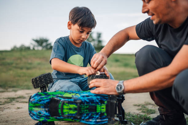 istock Boy repairing a tire on a broken toy car while his father is assisting him. 1971347155