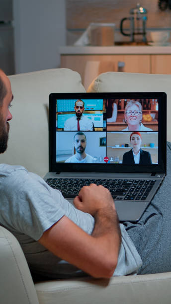 istock Comfortable man relaxing on couch while having online business conference 1971386258