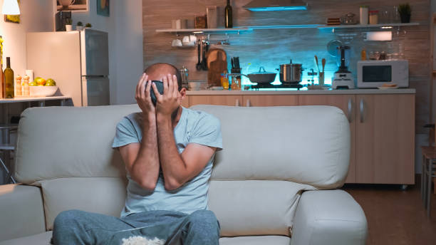 istock Concentrated man sitting in front of television while watching fun shows series 1971397701