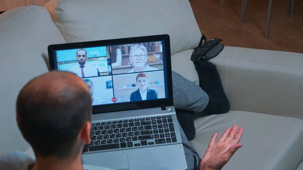 istock Back shot of tired man lying on sofa while chatting with teammates 1971406515