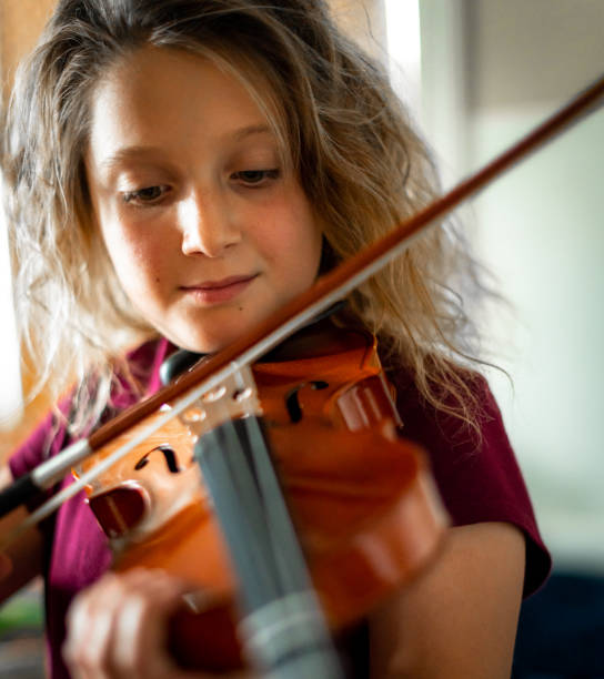 istock Serious elementary age musician, girl child practices playing the violin 1971410088