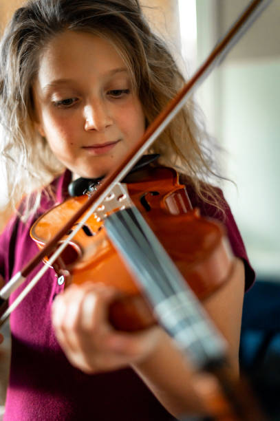 istock Serious elementary age musician, girl child practices playing the violin 1971410115