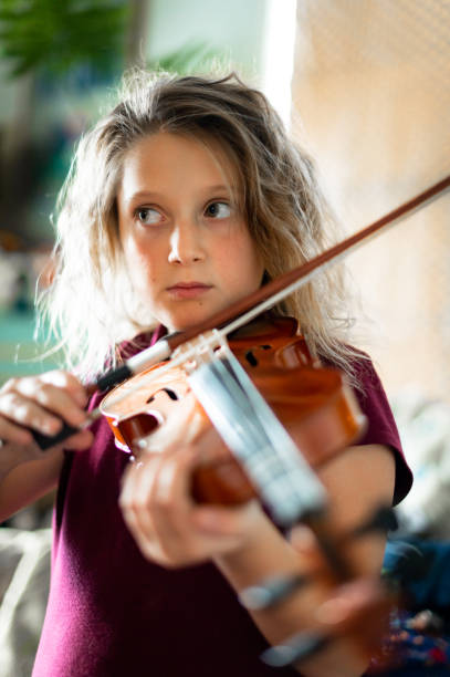 istock Serious elementary age musician, girl child practices playing the violin 1971413897