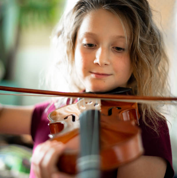 istock Serious elementary age musician, girl child practices playing the violin 1971417539