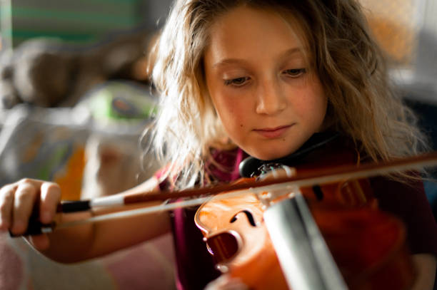 istock Serious elementary age musician, girl child practices playing the violin 1971441737
