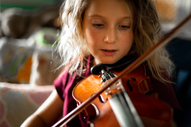istock Serious elementary age musician, girl child practices playing the violin 1971443325