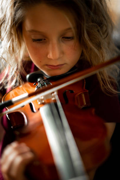 istock Serious elementary age musician, girl child practices playing the violin 1971443328