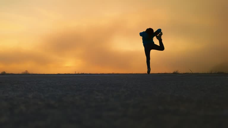 SLO MO Silhouette Woman in Ice Skates Spinning on Frozen Lake Cerknica Under Orange Sky During Golden Hour