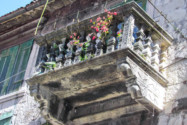 pintoresco balcón antiguo de piedra tallada decorado con flores en casa residencial en montenegro en una tarde soleada. primer plano - ancient past antique close up fotografías e imágenes de stock