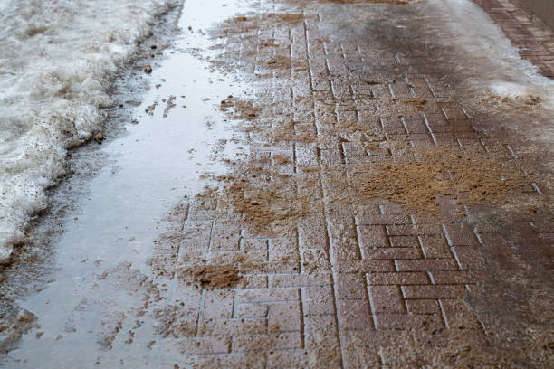 istock Road surface treated with technical salt and sand to prevent ice formation, salt puddles on the road 1971515517