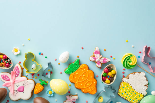 istock Easter-themed confectionery scene. Top view of a table featuring baking essentials like cookie cutters. Delightful gingerbreads, chocolate eggs, lollipops on a light blue surface with space for text 1971516604
