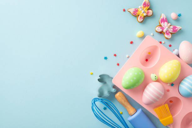 istock Easter Culinary Scene: Top view of baking table showcasing tools such as whisk, roller-pin, brush. Whimsical sweets, cookie cutters, chocolate eggs, sprinkles on light blue surface. Ideal for advert 1971516619