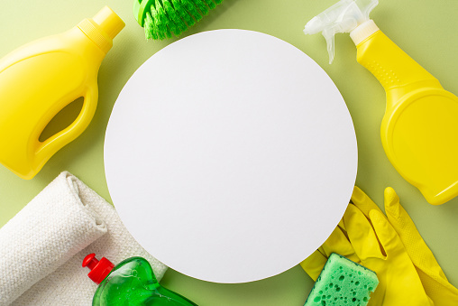 Unblemished tidiness motif. Top view of cleaning supplies - detergent products, dust cloth, rubber gloves, brush, and sponge on soothing green background. Adequate space for your custom text or promo