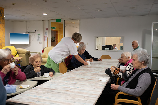 Caregivers serving coffee to seniors in a nursing home