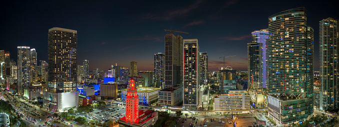View from above of brightly illuminated skyscraper buildings in downtown district of Miami Brickell in Florida, USA at night. American megapolis with business financial district.