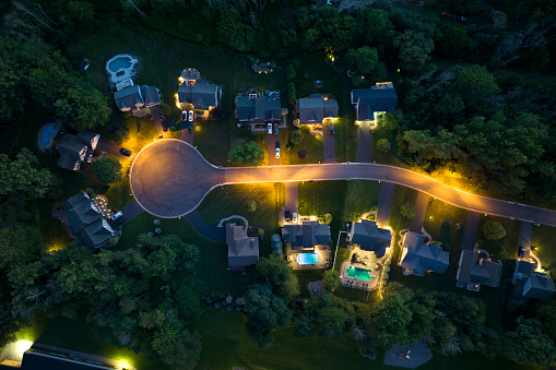 View from above of residential houses in living area in Rochester, NY at night. Illuminated american dream homes as example of real estate development in US suburbs.