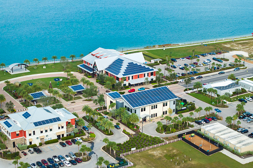 Florida office buildings with solar roof in small autonomous town. Blue photovoltaic panels for producing clean ecological electric energy. Investing in renewable electricity concept.