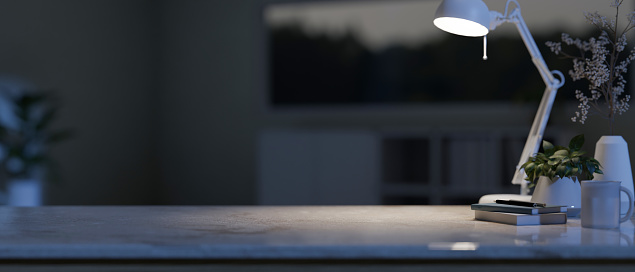 A tabletop with dim light from a table lamp, decor, and a copy space for displaying your product with a blurred dark living room in the background. home workspace at night. 3d render, 3d illustration